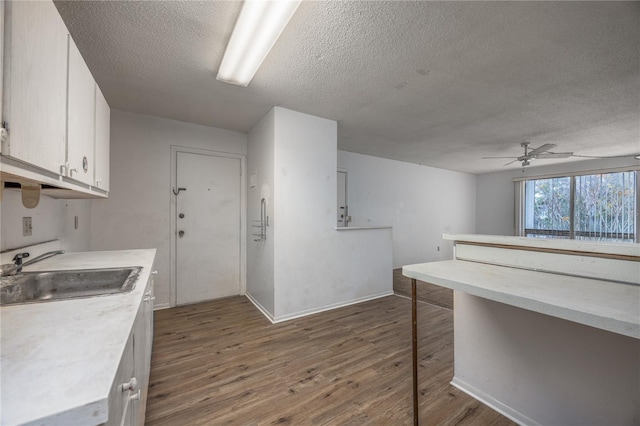 kitchen featuring dark hardwood / wood-style flooring, a textured ceiling, ceiling fan, sink, and white cabinetry