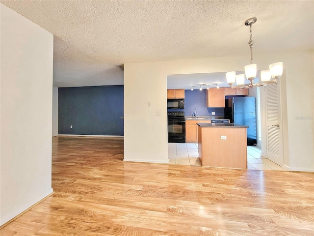 kitchen featuring black appliances, decorative light fixtures, light wood-type flooring, and sink