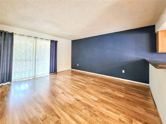 unfurnished living room featuring light hardwood / wood-style flooring and a textured ceiling