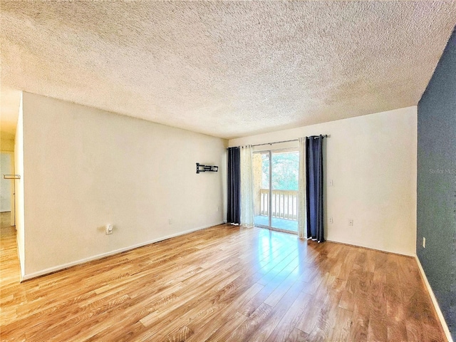 empty room with light hardwood / wood-style floors and a textured ceiling