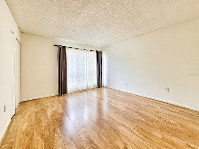 unfurnished room with light wood-type flooring and a textured ceiling