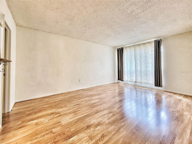 spare room featuring light hardwood / wood-style flooring and a textured ceiling