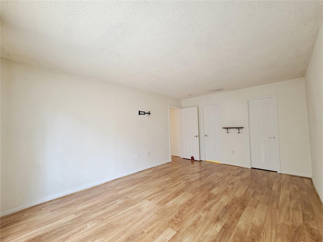 spare room with a textured ceiling and light hardwood / wood-style floors