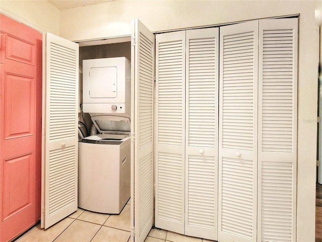 laundry area featuring light tile patterned flooring and stacked washer and dryer