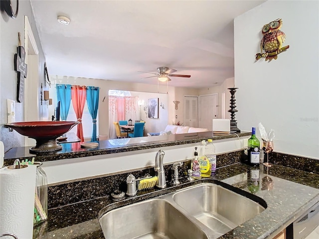 kitchen featuring ceiling fan, dark stone countertops, and sink