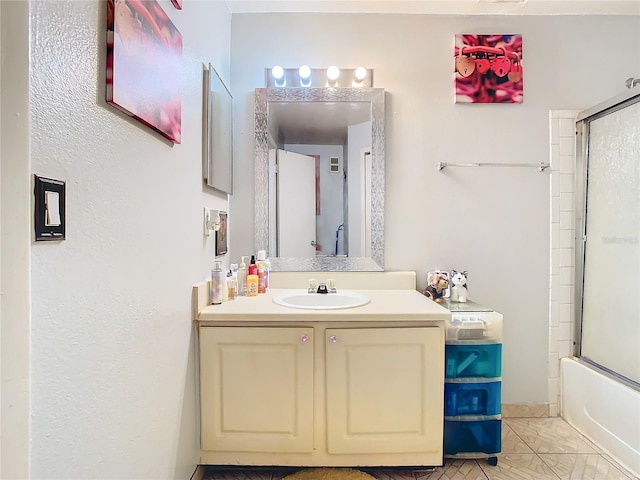 bathroom featuring tile patterned flooring, vanity, and enclosed tub / shower combo