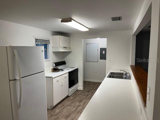 kitchen featuring white cabinetry, wood-type flooring, white appliances, and sink