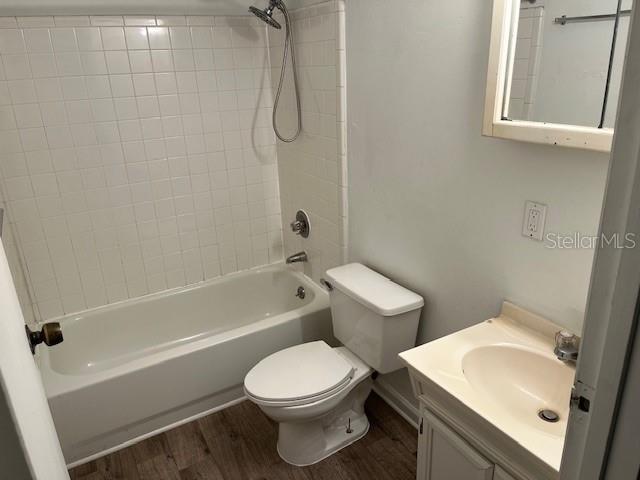 full bathroom with wood-type flooring, vanity, toilet, and tiled shower / bath combo