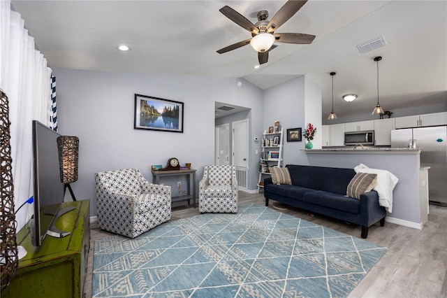 living room with a textured ceiling, ceiling fan, wood-type flooring, and lofted ceiling