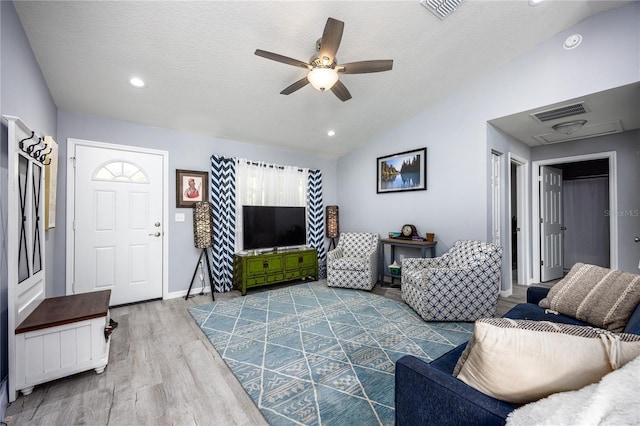 living room featuring ceiling fan, vaulted ceiling, a textured ceiling, and light hardwood / wood-style flooring