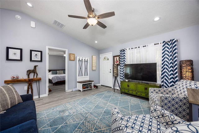 living room with hardwood / wood-style flooring, ceiling fan, lofted ceiling, and a textured ceiling