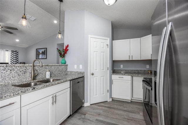 kitchen with appliances with stainless steel finishes, white cabinetry, lofted ceiling, and sink