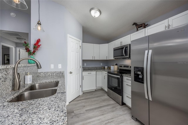 kitchen with lofted ceiling, white cabinets, sink, light wood-type flooring, and appliances with stainless steel finishes