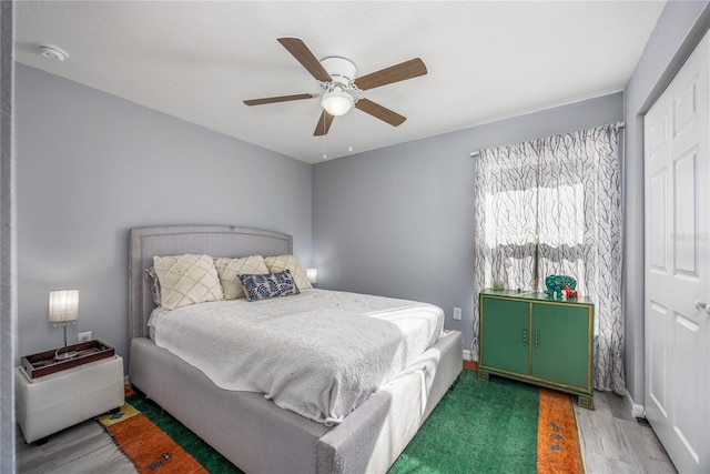 bedroom with ceiling fan, a closet, and wood-type flooring