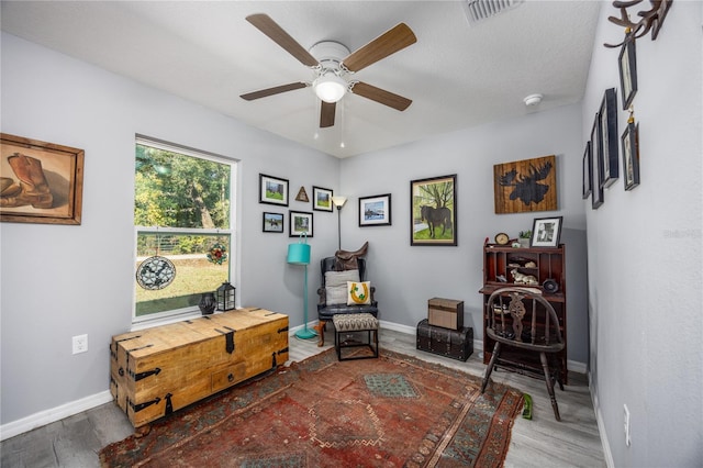 sitting room featuring ceiling fan, wood-type flooring, and a textured ceiling