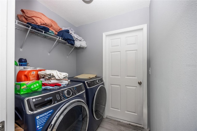 clothes washing area featuring washer and clothes dryer, a textured ceiling, and light hardwood / wood-style flooring