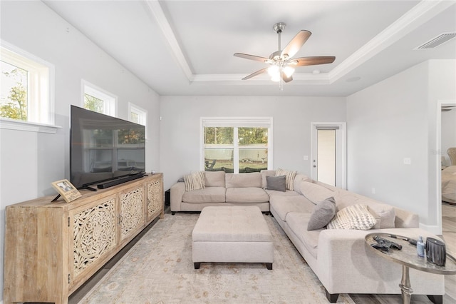 living room featuring ceiling fan, light hardwood / wood-style floors, and a raised ceiling