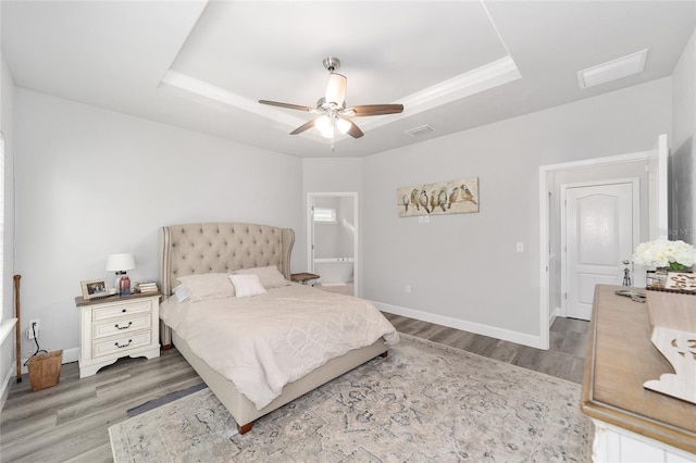 bedroom with hardwood / wood-style floors, ceiling fan, and a tray ceiling