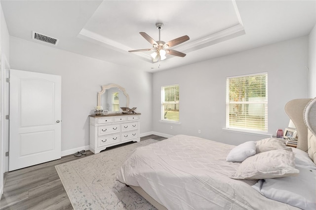 bedroom featuring hardwood / wood-style floors, a tray ceiling, and ceiling fan