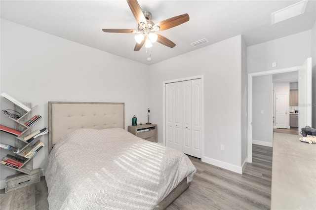 bedroom with ceiling fan, wood-type flooring, and a closet