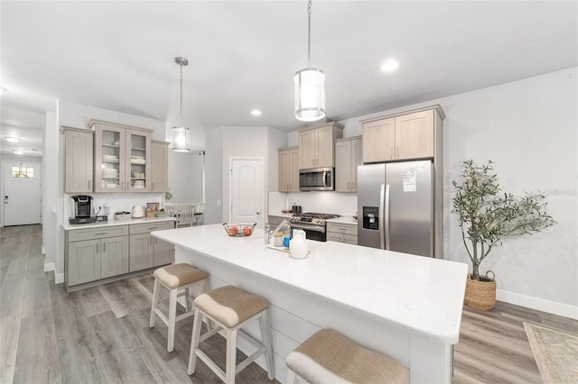 kitchen featuring a breakfast bar, a kitchen island with sink, stainless steel appliances, and decorative light fixtures