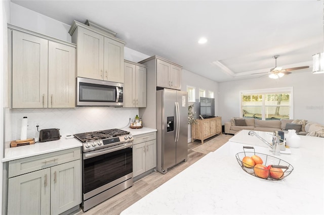 kitchen featuring tasteful backsplash, light hardwood / wood-style floors, stainless steel appliances, ceiling fan, and gray cabinets