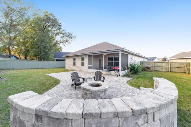 rear view of house featuring a patio, an outdoor fire pit, a lawn, and a sunroom