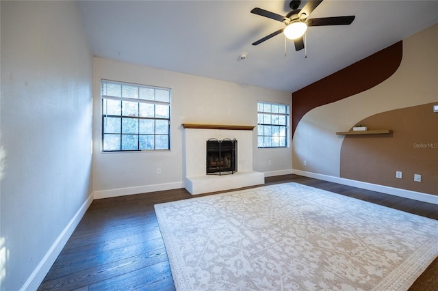 unfurnished living room with plenty of natural light, dark wood-type flooring, and ceiling fan