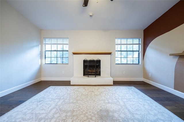 unfurnished living room featuring a wealth of natural light, ceiling fan, and dark hardwood / wood-style floors