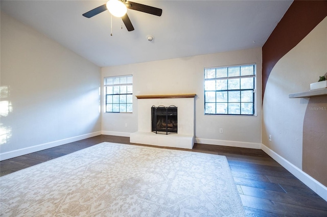 unfurnished living room with lofted ceiling, a wealth of natural light, dark wood-type flooring, and ceiling fan