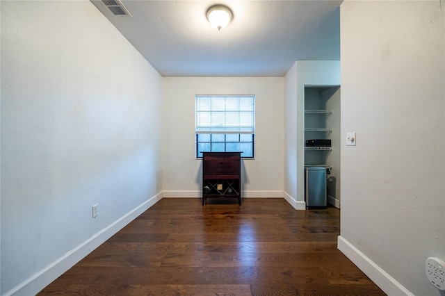 unfurnished living room featuring built in shelves and dark hardwood / wood-style flooring