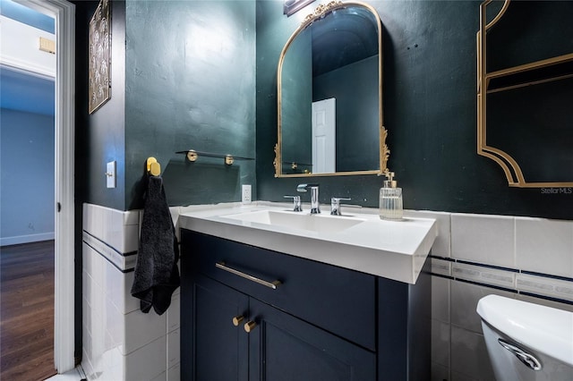 bathroom featuring hardwood / wood-style floors, vanity, tile walls, and toilet