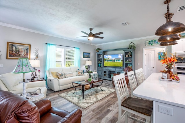 living room with hardwood / wood-style flooring, ceiling fan, and crown molding