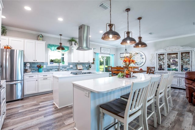 kitchen with a center island, stainless steel fridge, wood-type flooring, decorative light fixtures, and black stovetop