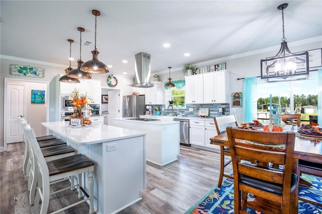 kitchen featuring a center island, light hardwood / wood-style floors, decorative light fixtures, white cabinets, and appliances with stainless steel finishes