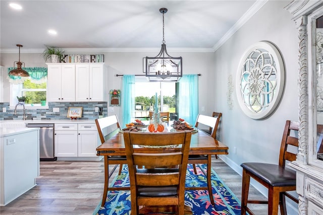 dining area with a chandelier, light hardwood / wood-style flooring, ornamental molding, and sink