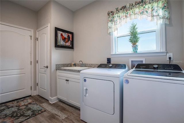 laundry room featuring hardwood / wood-style flooring, cabinets, sink, and washing machine and clothes dryer