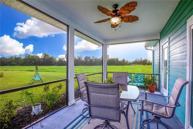 sunroom / solarium with ceiling fan and a rural view