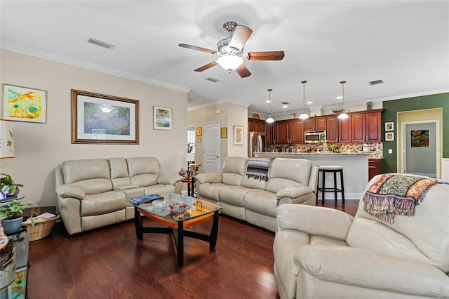 living room with ornamental molding, ceiling fan, and dark wood-type flooring