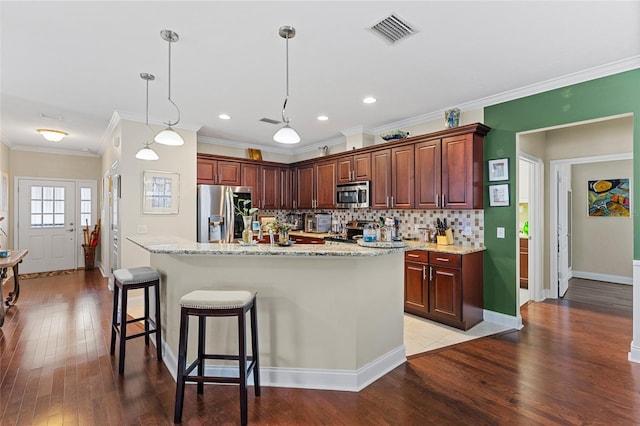 kitchen featuring stainless steel appliances, light hardwood / wood-style flooring, an island with sink, decorative light fixtures, and ornamental molding