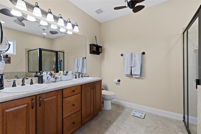 bathroom with vanity, a shower with door, tile patterned flooring, ceiling fan, and toilet
