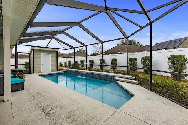 view of swimming pool with a lanai, pool water feature, a patio, and a shed