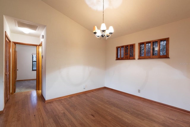 empty room with wood-type flooring, an inviting chandelier, and lofted ceiling