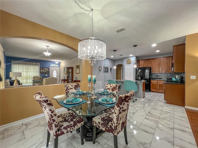 dining area with a textured ceiling and a notable chandelier