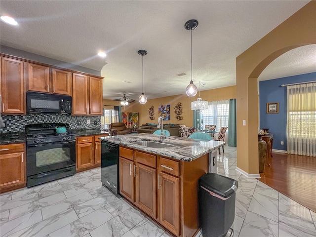 kitchen with black appliances, hanging light fixtures, sink, and a wealth of natural light