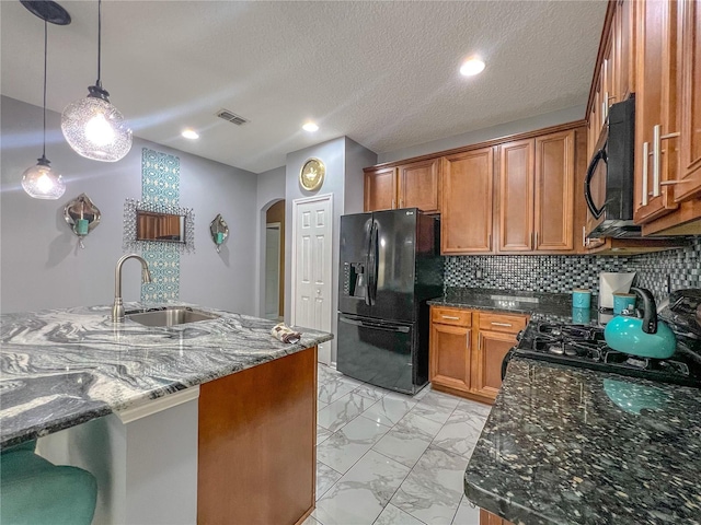 kitchen with backsplash, dark stone counters, sink, black appliances, and decorative light fixtures