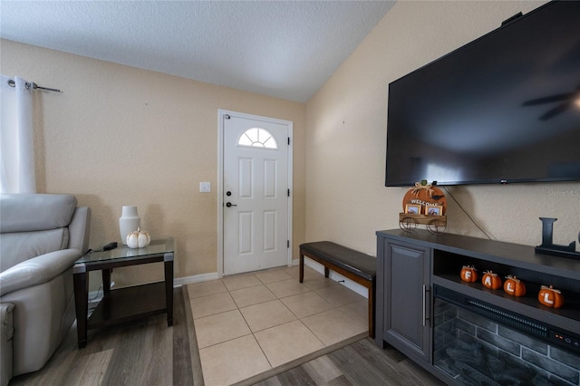 entrance foyer with a textured ceiling, light hardwood / wood-style flooring, and lofted ceiling