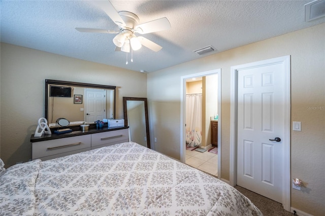 bedroom with a textured ceiling, ensuite bathroom, ceiling fan, and light colored carpet