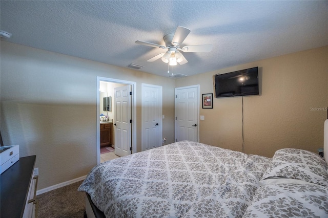 carpeted bedroom with ensuite bath, ceiling fan, and a textured ceiling