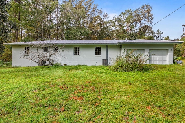 back of property featuring central air condition unit and a yard